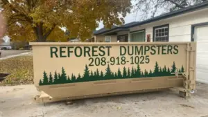 Reforest Dumpsters container on a residential driveway with autumn leaves and a house in the background