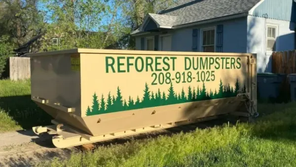 Reforest Dumpsters container parked outside a small blue house on a residential street