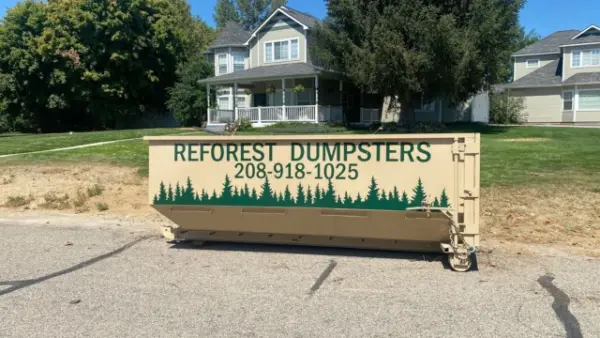 Reforest Dumpsters container parked on the street in front of a two-story home with a covered porch