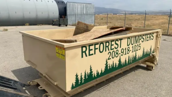 Reforest Dumpsters container loaded with wood board debris in a fenced industrial yard